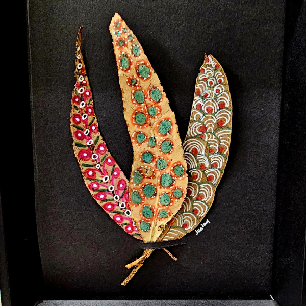 Three painted leaves neatly arranged in a black frame