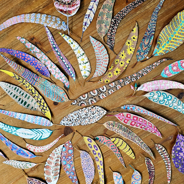 A collection of painted leaves laid out on a wooden floor